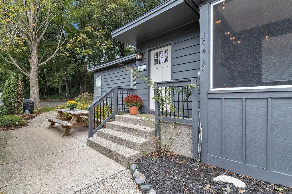 A house with a front porch, a wooden bench, a potted plant, and a mailbox.