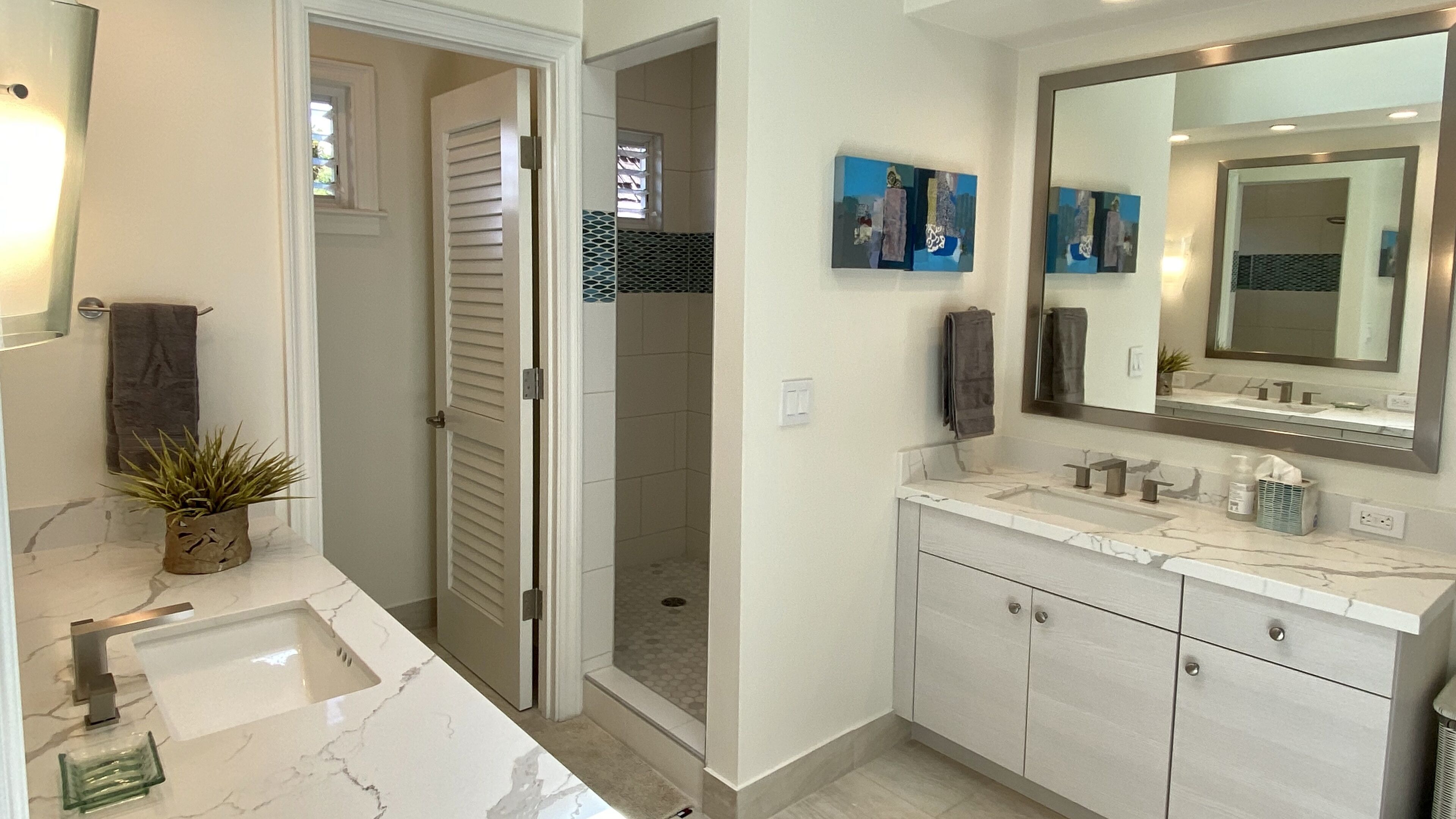 A modern bathroom with a marble sink, a large mirror, and a walk-in shower.