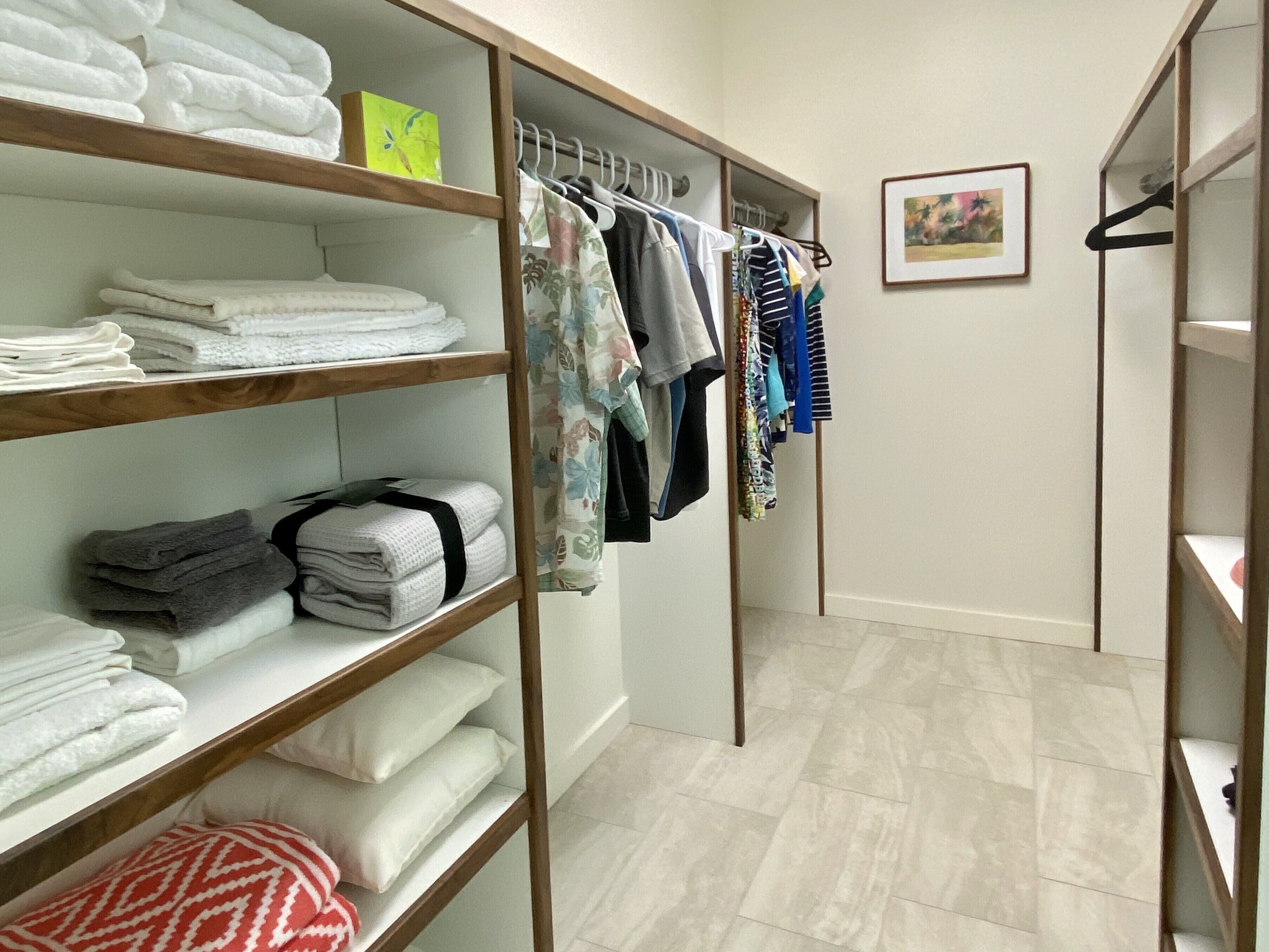 Ein begehbarer Kleiderschrank mit Regalen für gefaltete Handtücher und einer Kleiderstange.
