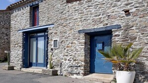 Un bâtiment en pierre avec deux portes bleues et une petite fenêtre.
