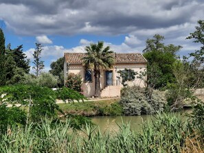 A house with a tiled roof, surrounded by lush greenery and a pond. - Opuntia (Téoulièro), air-conditioned house in a quiet Mediterranean village (Escales)