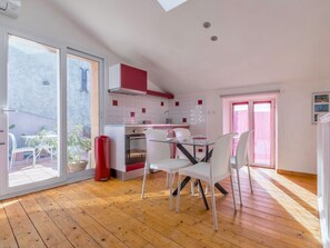 A modern kitchen with a dining area, wooden flooring, and a view through a sliding glass door. - Opuntia (Téoulièro), air-conditioned house in a quiet Mediterranean village (Escales)