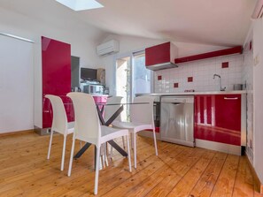 A modern kitchen with a dishwasher, a red and white color scheme, and a dining area with white chairs. - Opuntia (Téoulièro), air-conditioned house in a quiet Mediterranean village (Escales)