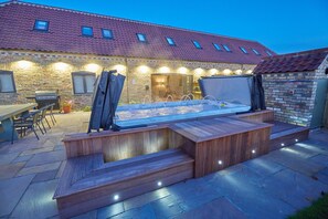 A hot tub with a wooden bench, a barbecue grill, and a stone wall. - Holly Tree Barn, Ashlin Farm Barns (Lincoln)
