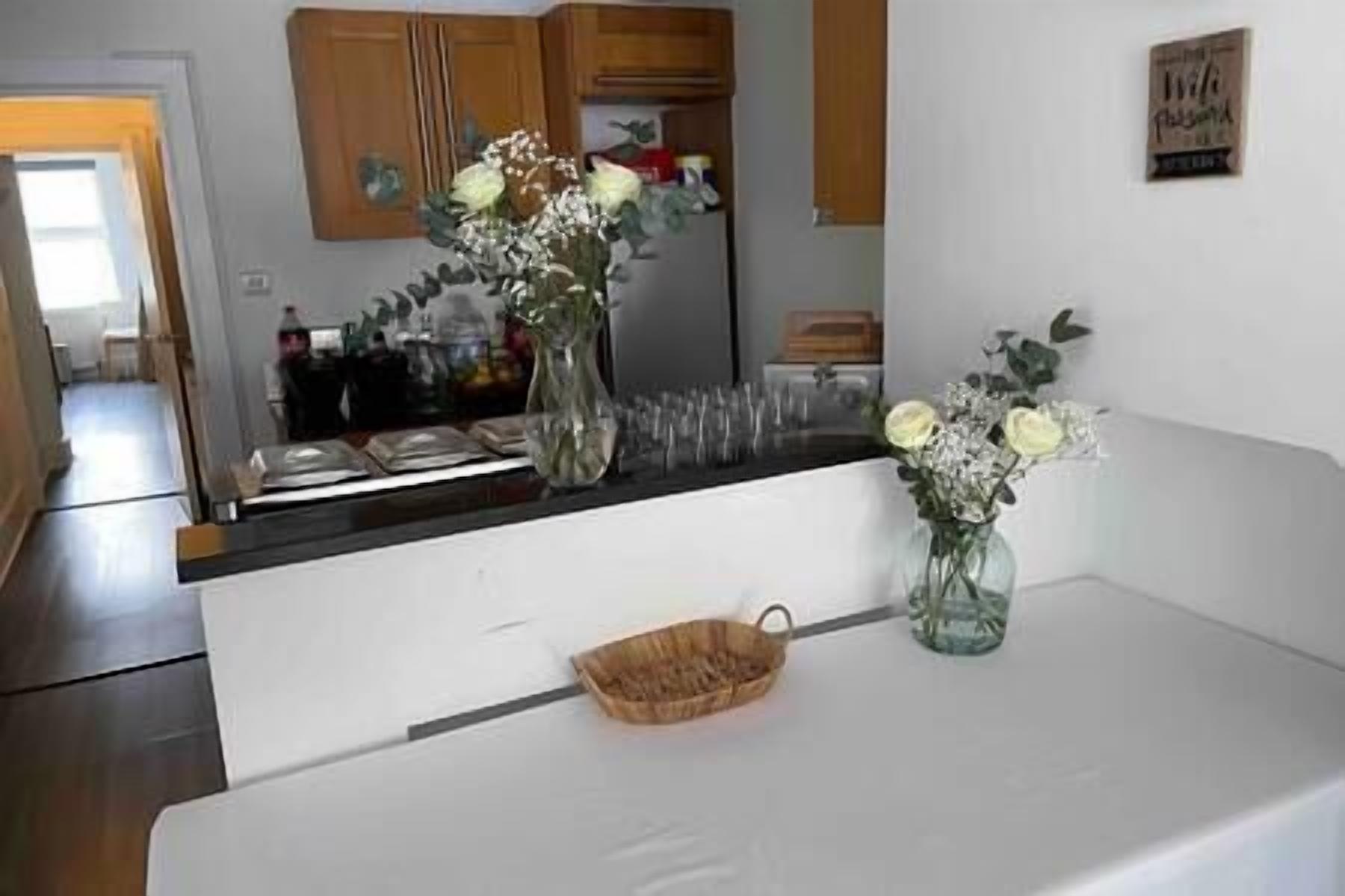 Une cuisine avec des armoires blanches, un plan de travail en bois et un vase rempli de fleurs.