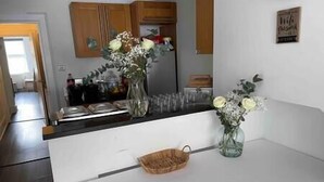 A kitchen with white cabinets, a wooden countertop, and a vase with flowers. - Bournemouth hot tub and sauna holiday let (Bournemouth)