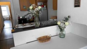 Une cuisine avec des armoires blanches, un plan de travail en bois et un vase rempli de fleurs.