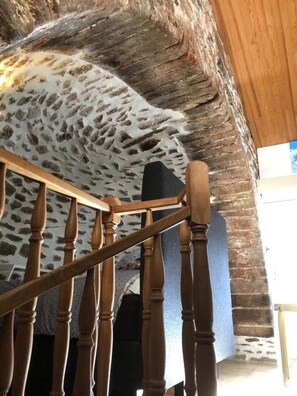 A staircase with wooden balusters and a stone wall.