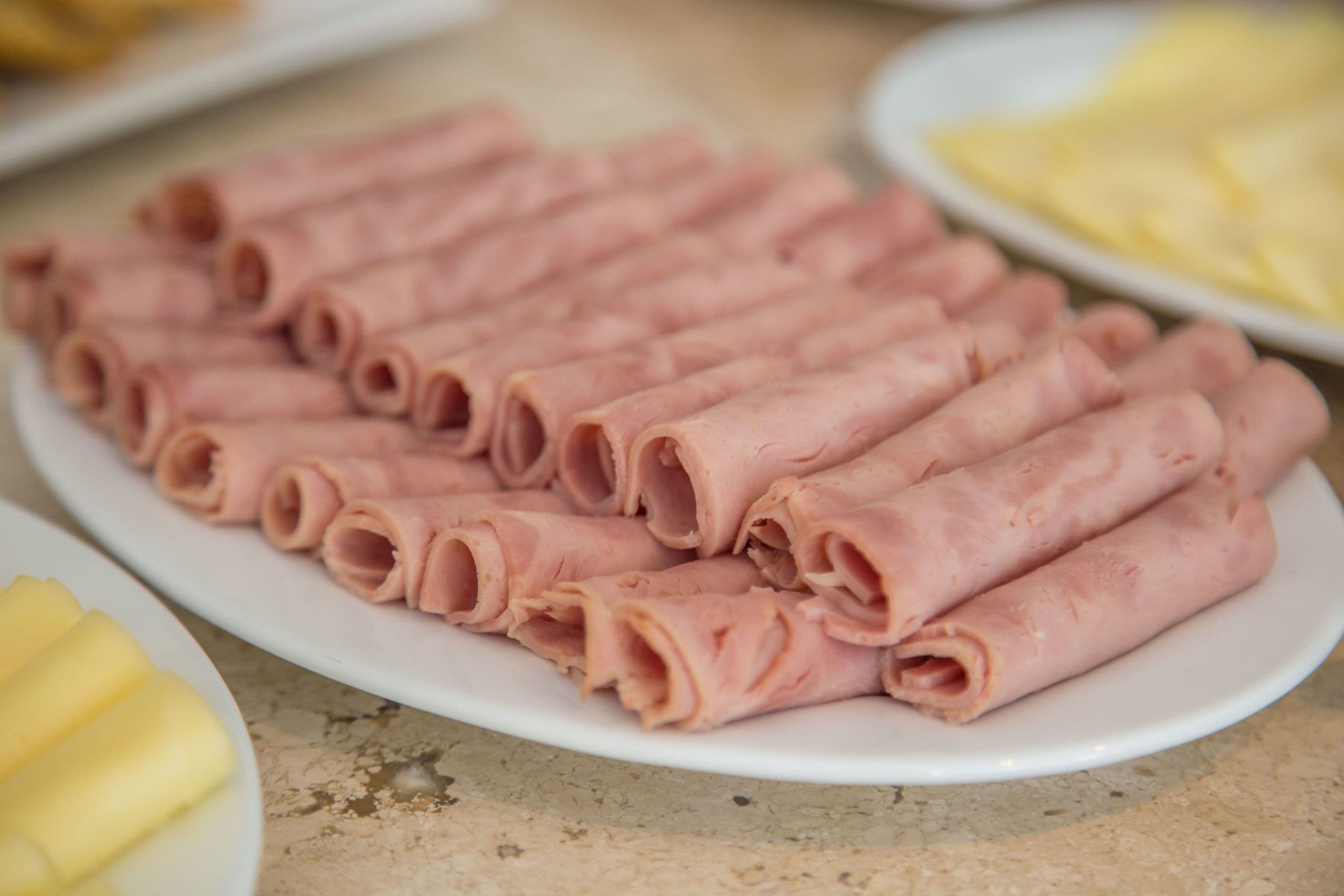 A plate of sliced ham arranged neatly on a white plate.