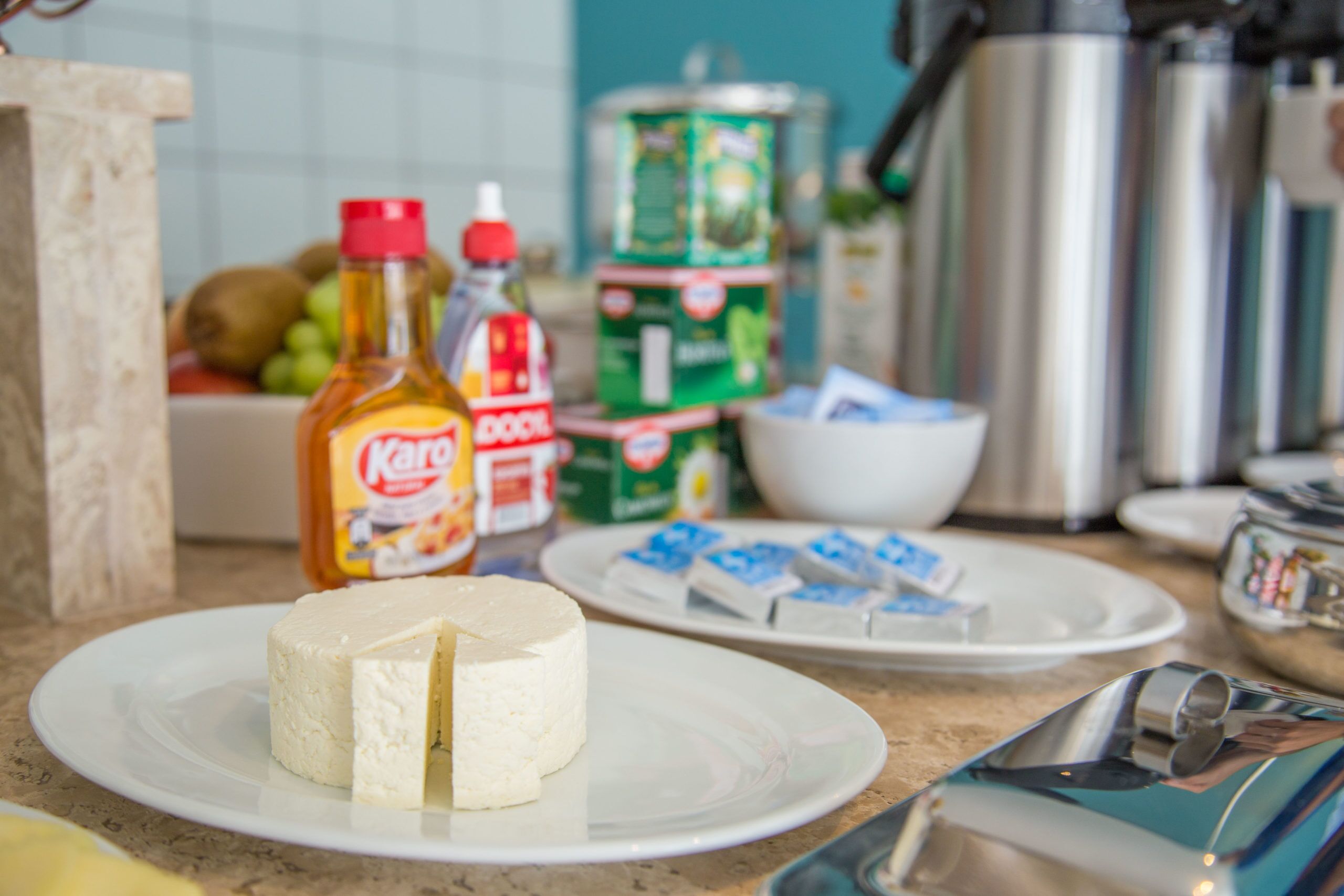 A kitchen counter with a plate of cheese, condiments, and a coffee maker.