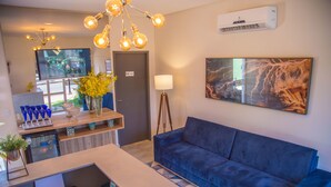 Rebedor modern d'hotel amb un sofà blau, una taula de recepció, un televisor gran i un quadre a la paret.