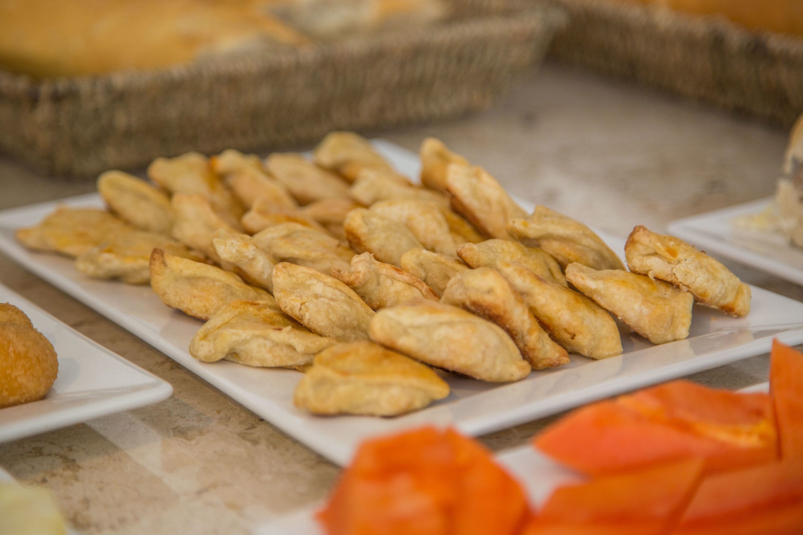 Una mesa de buffet con diversos alimentos, incluyendo pasteles y una cesta al fondo.