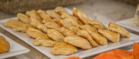Una mesa de buffet con diversos alimentos, incluyendo pasteles y una cesta al fondo.