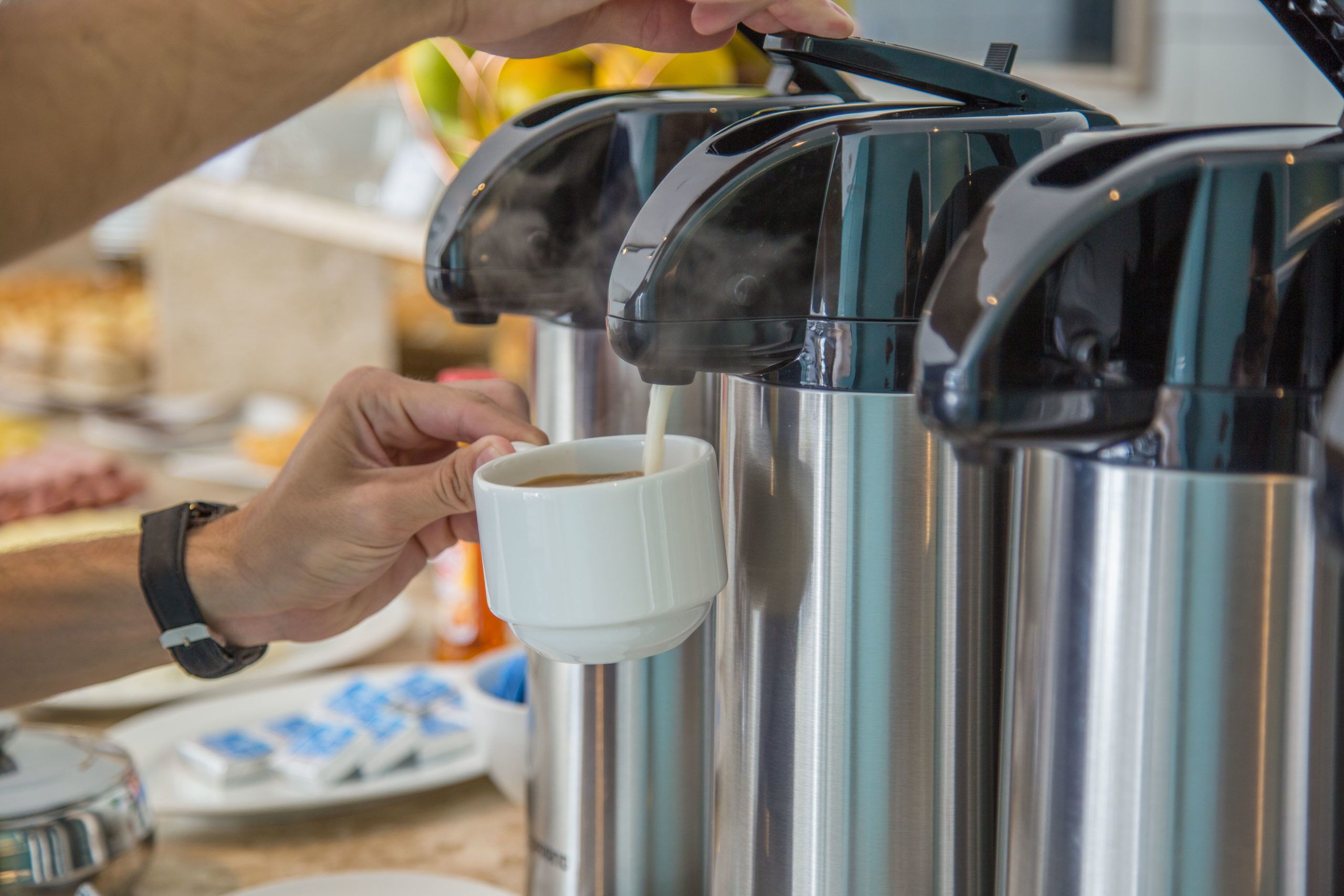 Iemand giet koffie uit een apparaat in een kopje.