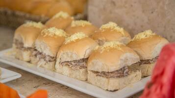 A plate of pulled pork sandwiches with shredded cheese on buns.