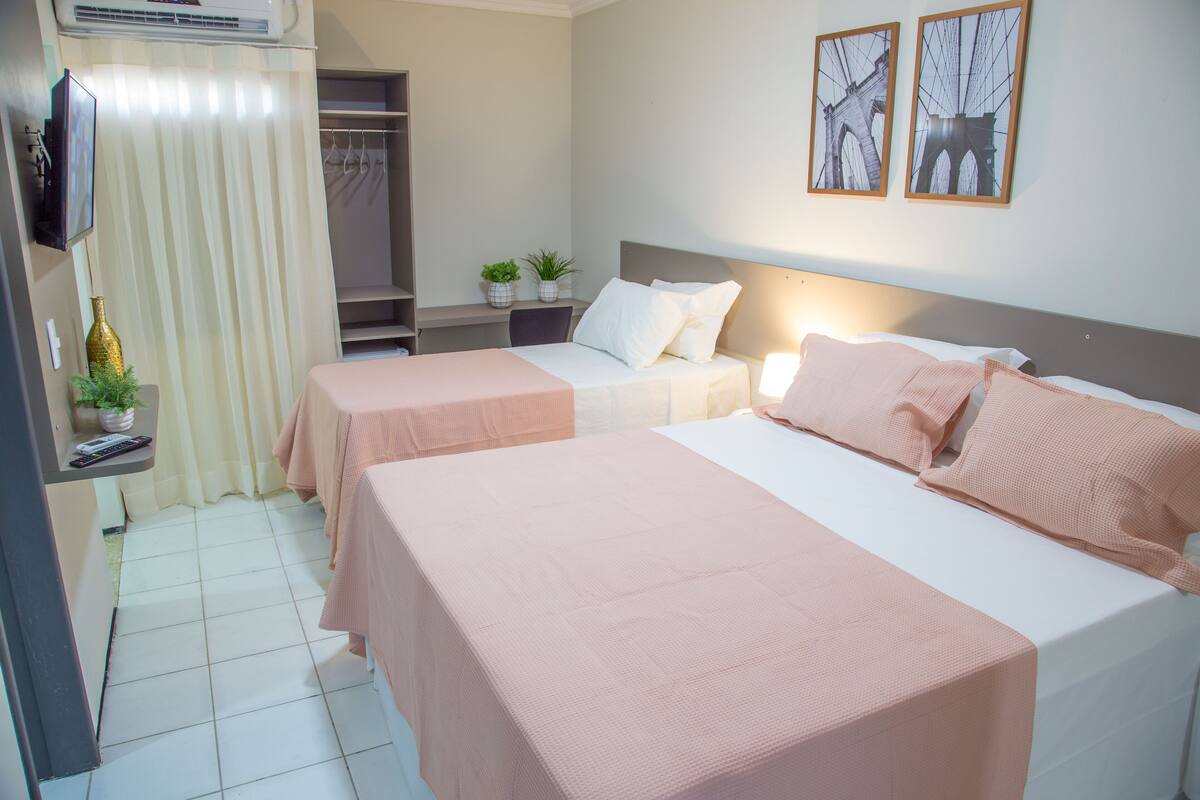 Habitación de hotel con dos camas, televisión, escritorio y armario.