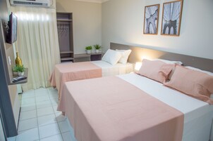 Habitación de hotel con dos camas, televisión, escritorio y armario.