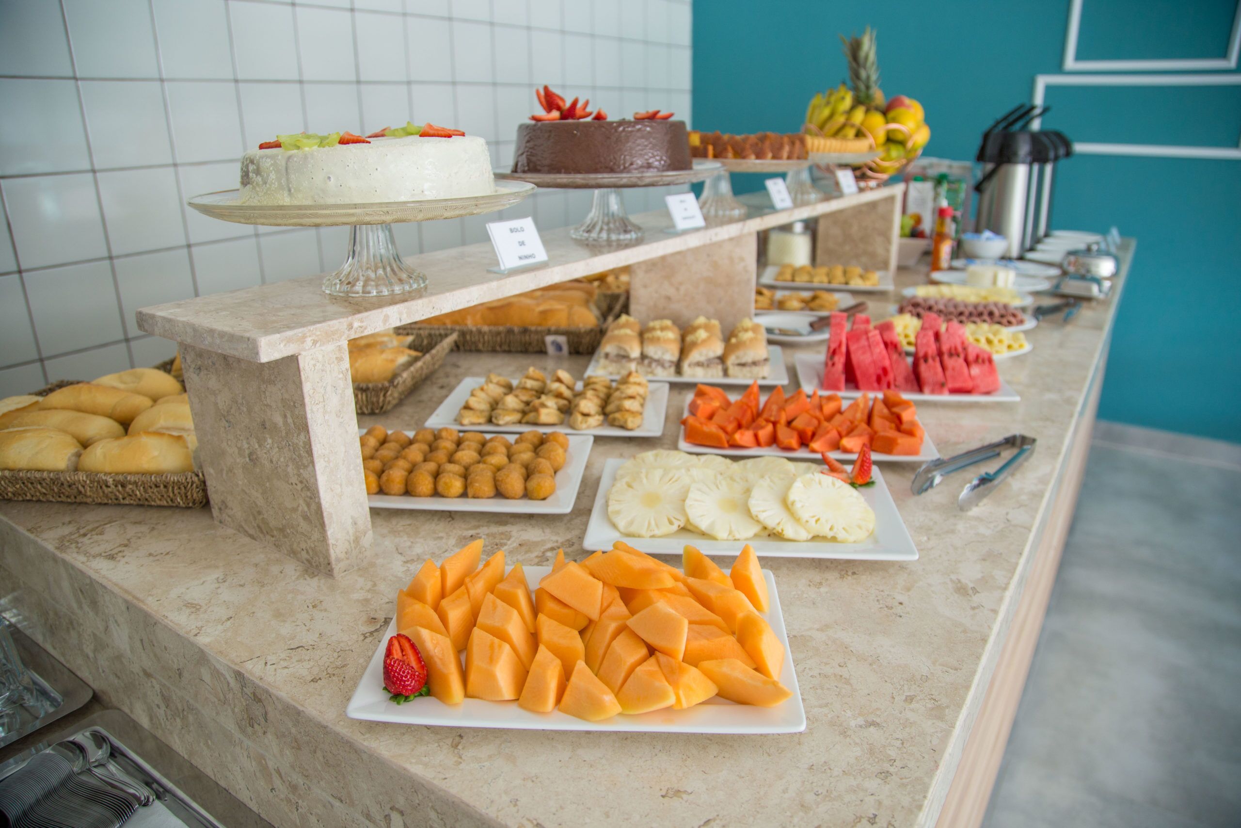 Un bufé con diversas opciones de comida, incluyendo pasteles, productos de repostería, frutas y verduras.