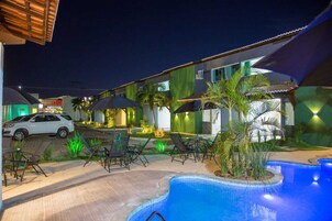Un hotel con piscina, mobiliario exterior y palmeras.