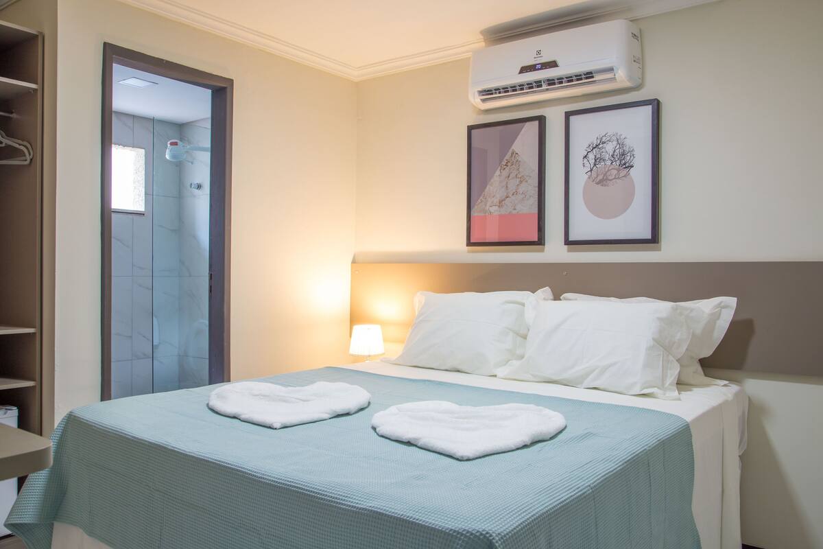 Una habitación de hotel con cama, baño y aire acondicionado de pared.