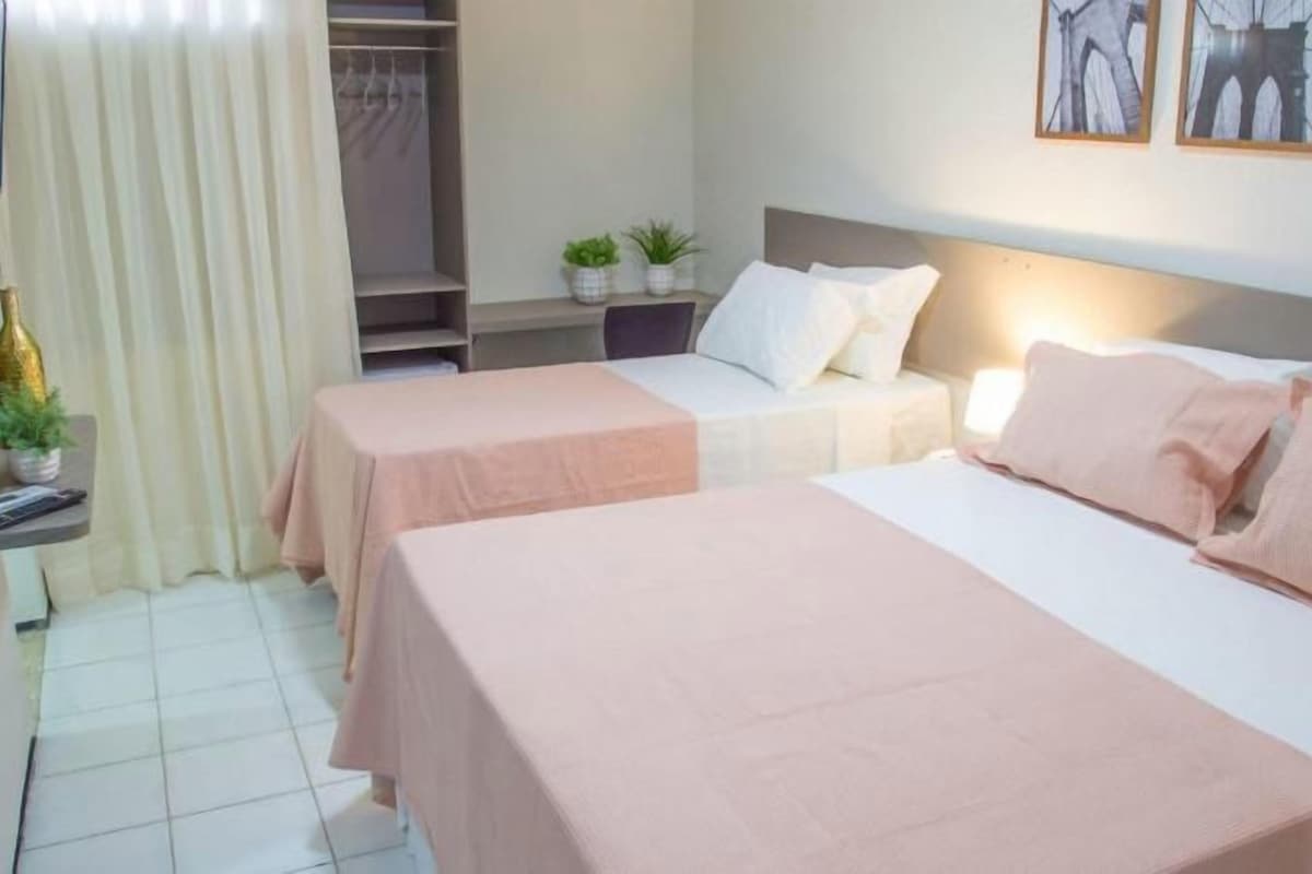 Una habitación de hotel con dos camas, un escritorio, un armario y un televisor.
