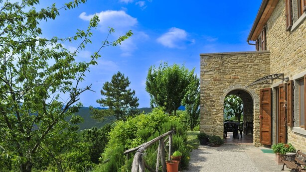 Un edificio de piedra con un arco que da a un camino de grava.