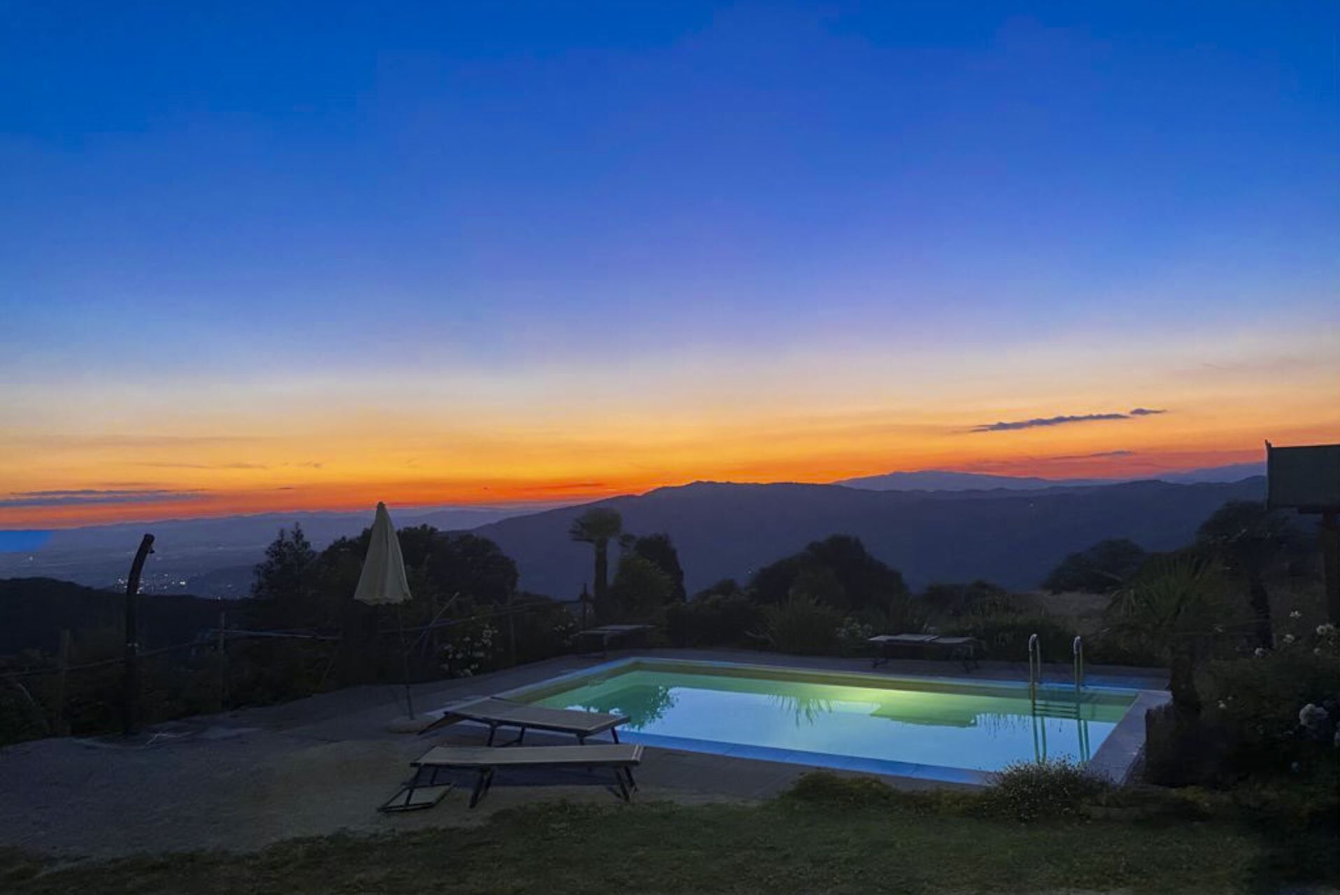 Une piscine offrant une vue sur les montagnes lointaines au coucher du soleil.