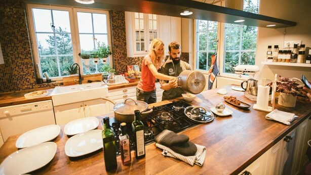 Una cocina moderna con una isla grande, armarios blancos y vistas a zonas verdes.