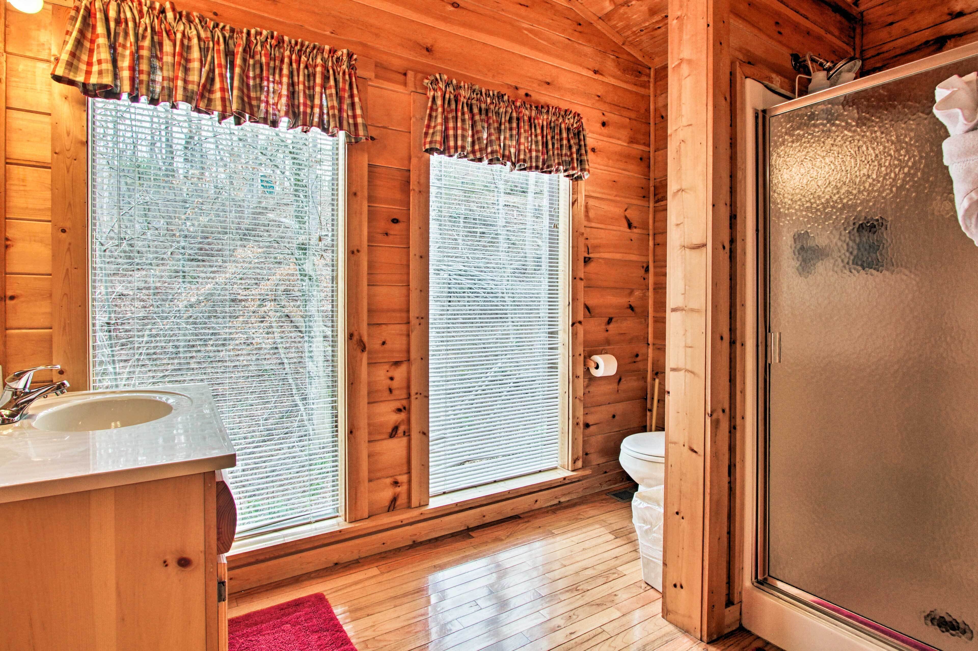 A wooden cabin bathroom with a sink, toilet, and shower.
