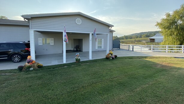 Ein zweistöckiges Haus mit überdachter Veranda, Garage und umzäunter Garten.