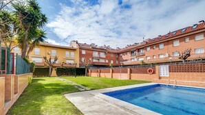 Un edificio residencial con piscina, césped cuidado y pared de ladrillo con boya salvavidas.