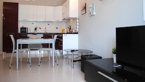 A modern kitchen with white cabinets, a dining table with chairs, a small round table, and a flat-screen TV. - Bnbook-Metropolitan Expo Flat 4 Bilocale con wifi veloce (Rho)