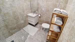 Un bagno moderno con lavandino, water e ripiano in legno con asciugamani.