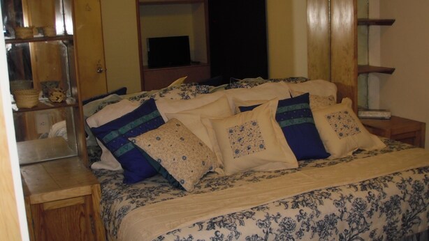 Une chambre à coucher avec un lit, une tête de lit en bois et un miroir au-dessus.