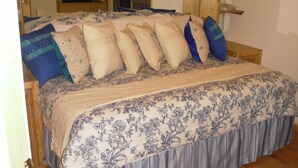 Une chambre à coucher avec un lit, des oreillers, une tête de lit en bois et une fenêtre.