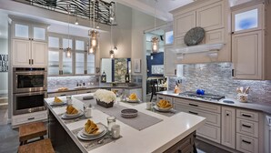 A modern kitchen with stainless steel appliances, a large island, and pendant lighting.