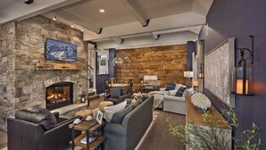 A cozy living room with a stone fireplace, a sofa set, and a dining area.