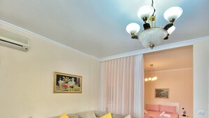 A living room with a sectional sofa, a ceiling fan, and a painting on the wall. - Fantastic Beach View at ARIEL’s HOUSE (Durrës)