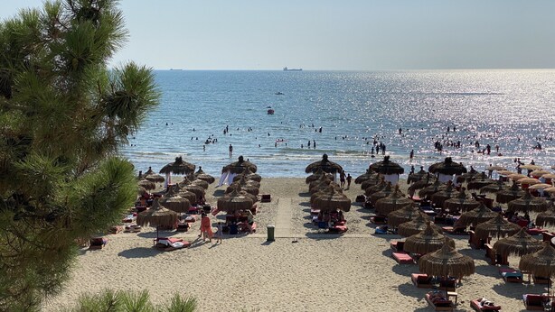 A beach with thatched umbrellas and lounge chairs, a sandy shore, and the sea in the background. - Fantastic Beach View at ARIEL’s HOUSE (Durrës)