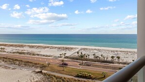 Eine Küstenstraße mit Palmen und einem Strand im Hintergrund.
