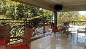 An outdoor patio area with wicker furniture and a railing. - Royal Cashrise lodge (Kabwe)