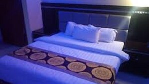 A hotel room with a large bed, a headboard, and a bedside table. - Royal Cashrise lodge (Kabwe)