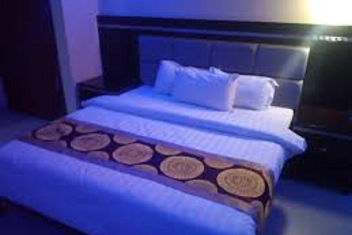 A hotel room with a large bed, a headboard, and a bedside table.