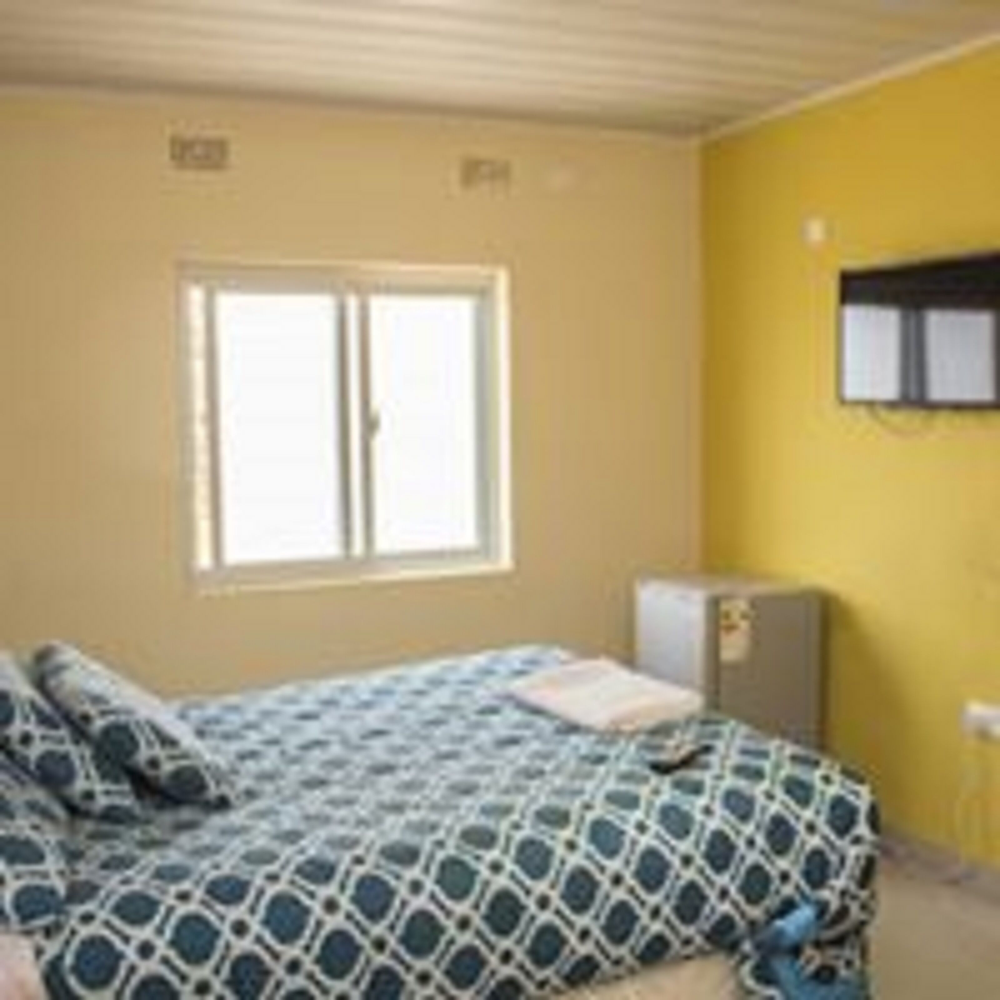 Una habitación con cama, ventana y televisor montado en la pared.