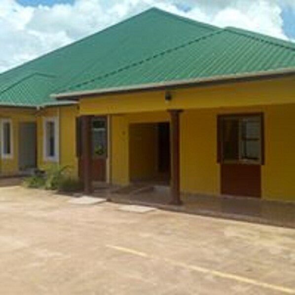 A building with a green roof and yellow walls, featuring a single entrance and a visible door.