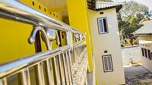 A yellow building with a balcony and a stone wall. - Royal Cashrise lodge (Kabwe)