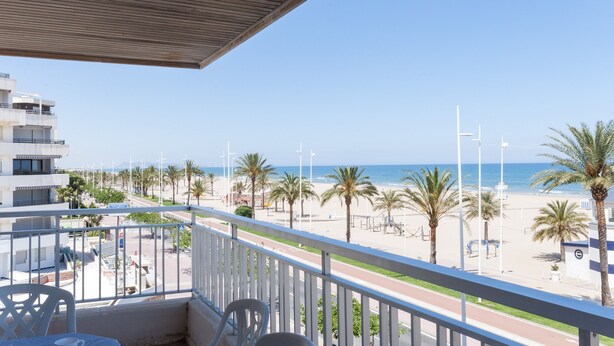 A balcony with a view of a beach, palm trees, and a clear sky. - PIROPO - Apartment with sea views in Playa de Gandia. (Grau i Platja)