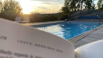 Un libro abierto con vista a una piscina y sillas de descanso.