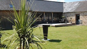 Un edificio de piedra con un patio césped y una terraza.