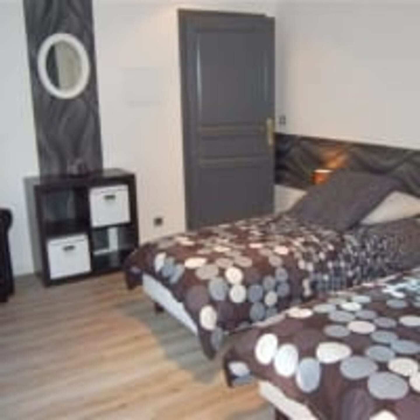 A bedroom with two beds, a dresser, and a door.
